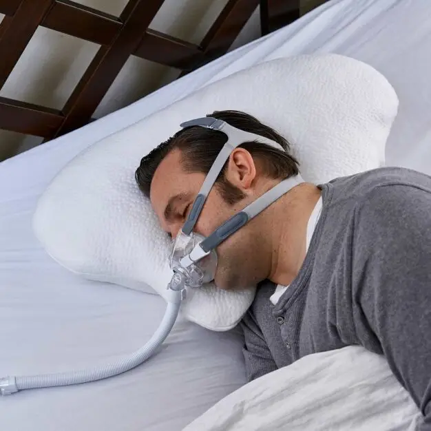 Seitenschläfer mit CPAP-Maske schläft auf dem Nachtwächter-Kissen LINA, die Maske hat Platz